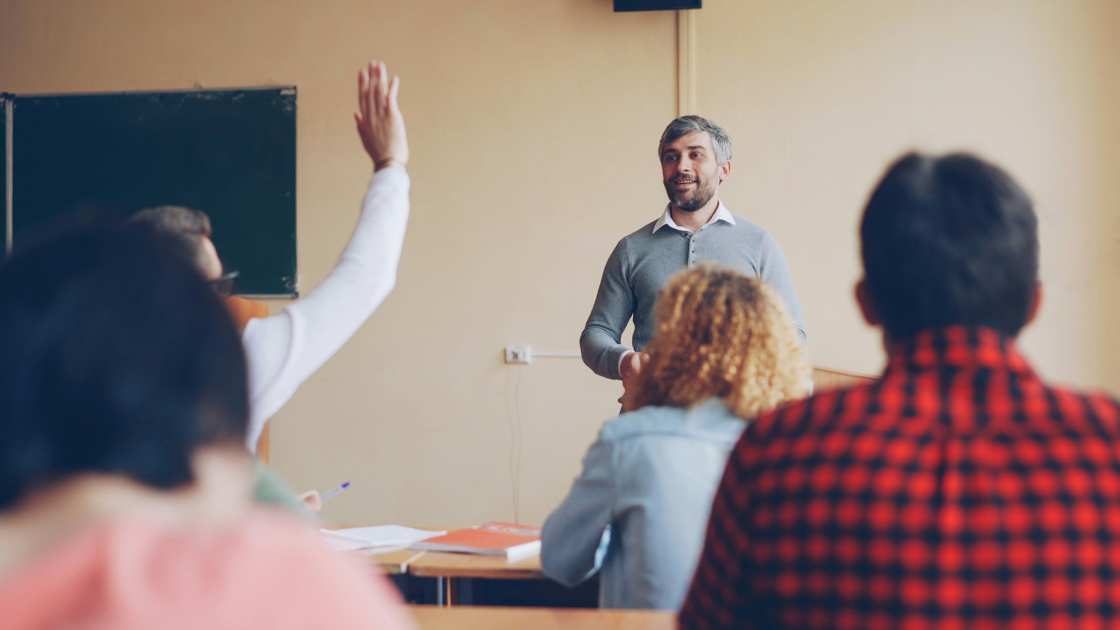 Student steekt hand op om extra uitleg te vragen aan docent